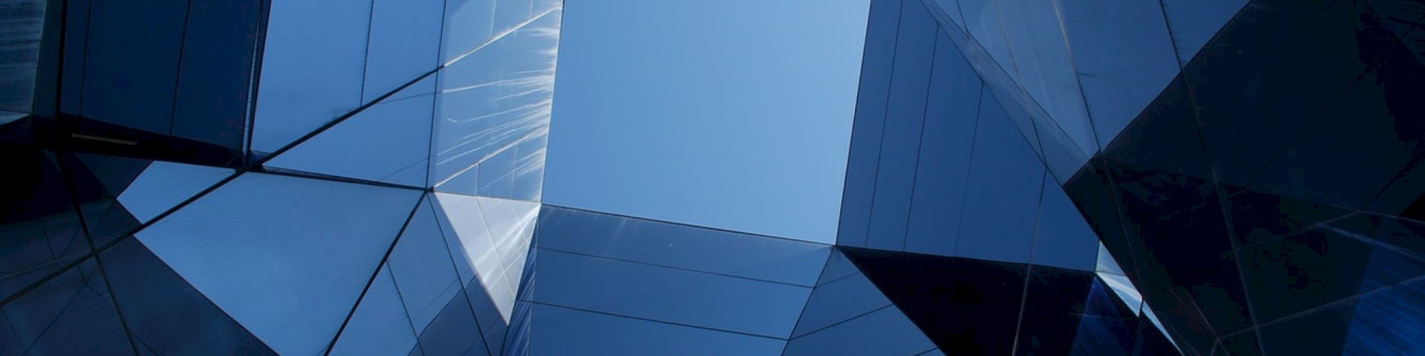 Geometric architecture with reflective glass surfaces creating a skylight view to the sky.