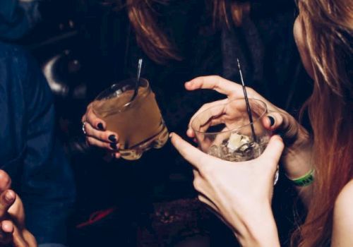 People are gathered, holding drinks with ice, chatting and laughing, possibly at a social event or party, creating a lively atmosphere.