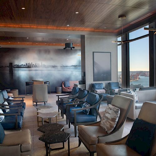 A modern lounge with stylish seating, large windows offering a scenic view, and ambient lighting enhancing the relaxed atmosphere.
